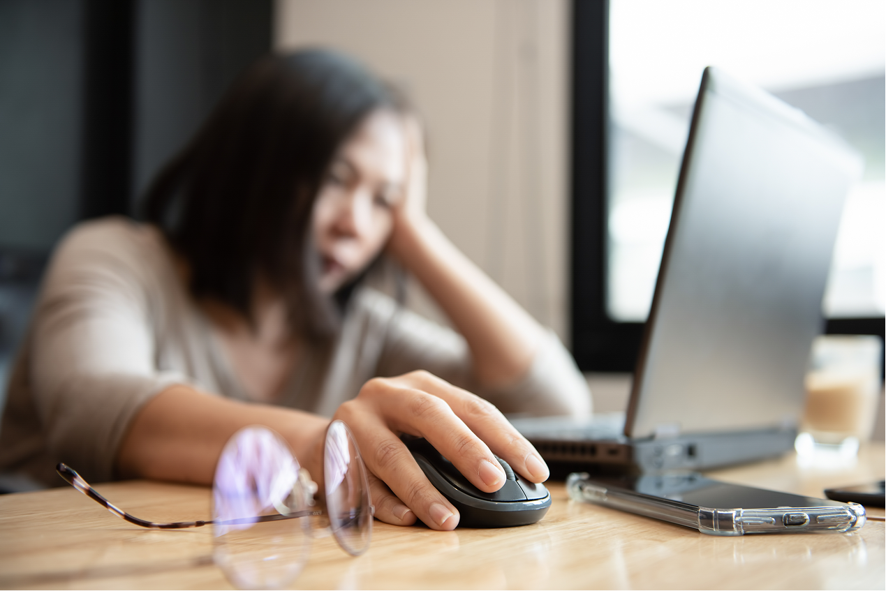 A lady looking distressed while staring at her laptop.
